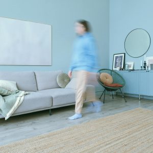 Blurred figure moves in a stylish, minimalist living room with blue accents.